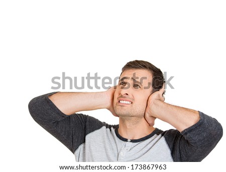 Closeup portrait of young man, student, worker, employee covering his ears from loud noise, having headache isolated on white background. Conflict resolution. Negative human emotions, face expressions