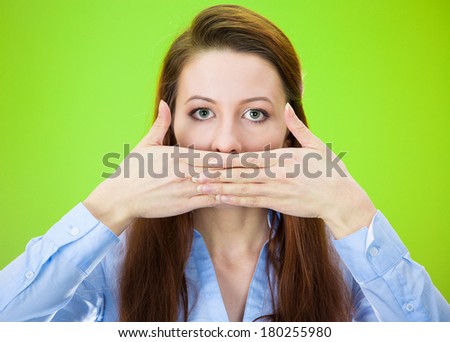 Closeup portrait of young woman covering closed mouth, open eyes. Speak no evil concept, isolated on green background. Negative human emotions, facial expressions signs and symbols. Media news coverup