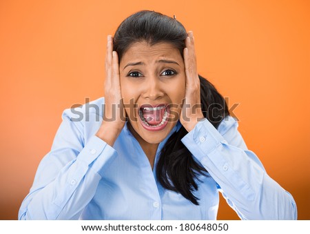 Closeup portrait of worried, stressed, overwhelmed young woman, funny looking girl, covering her ears, screaming going crazy, isolated orange background. Human emotions, facial expressions, reaction