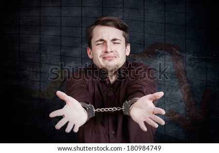 Closeup portrait of crying business man, former banker, wall street employee, broker, fund manager, criminal arrested with handcuffs isolated on grey background with declining stock market chart.