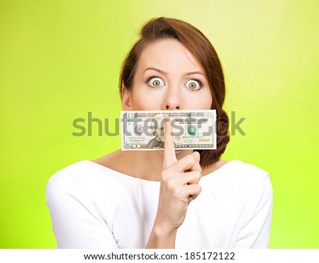 Closeup portrait young corrupt, secretive woman in white dress with twenty dollar bill taped to mouth, showing shhh sign, isolated green background. Bribery concept in politics, business, diplomacy