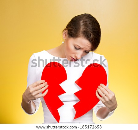 Closeup portrait young, troubled, sad, confused woman, holding broken heart in hands, about to cry, isolated yellow background. Negative human emotions, facial expression, feelings, attitude, reaction