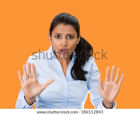 Closeup portrait, furious, mad, angry, annoyed, displeased young woman raising hands up to say no, stop right there, isolated orange background. Negative human emotion facial expression sign symbol