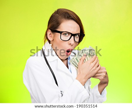 Closeup portrait grumpy greedy miserly health care professional, female doctor holding, protecting money dollars in hand, isolated green background. Negative emotions, facial expressions, human nature
