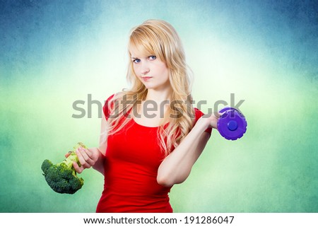 Closeup portrait, unhappy, annoyed, grumpy, displeased, young woman, girl with disgust on face, holding green broccoli, dumbbell in hands, questioning healthy life style recommendations. Expression