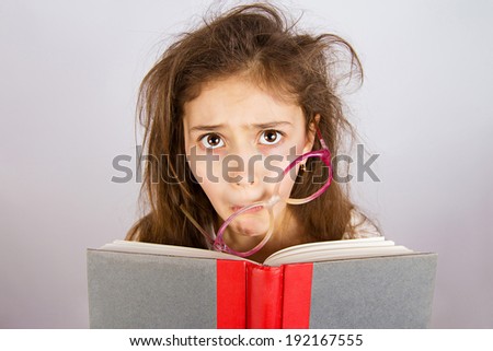 Closeup portrait sad, unhappy, stressed tired, overwhelmed, funny looking little girl with messed up glasses, holding book isolated grey background. Human facial expression, emotion, feeling, attitude