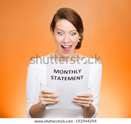 Closeup portrait happy excited young business woman looking at monthly statement glad to pay off bills, isolated orange background. Positive emotions, facial expressions. Financial success, good news