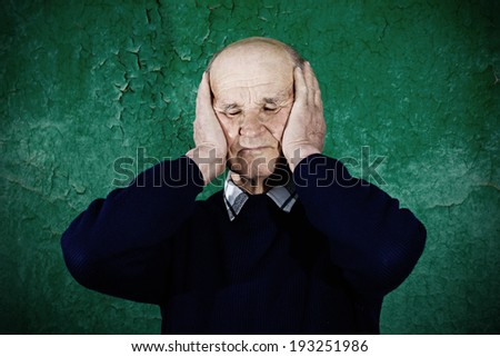 Closeup portrait, headshot, senior mature, peaceful, tranquil, relaxed, old man covering his ears, closed eyes, isolated green wall background. Hear no evil concept. Human emotions, facial expressions