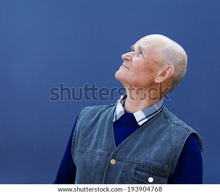 Closeup portrait senior, elderly, mature man, grandfather looking up with hope, thinking, daydreaming, isolated blue background. Human facial expressions, emotions, feelings, reaction life perception