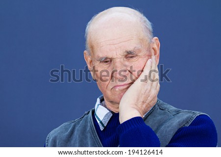 Closeup portrait senior, elderly, mature, old sad depressed man, deep in thought, thinking, realizing truth, looking down isolated blue background. Human face expressions, emotions, feeling, reaction