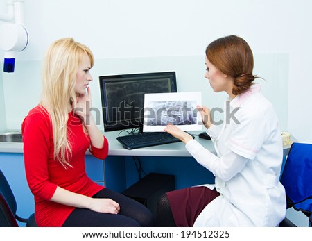 Closeup portrait female health care professional, dentist, holding showing panoramic dental X-ray, consulting woman patient having toothache.