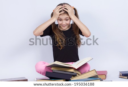 Closeup portrait happy, excited, smiling, funny looking little girl, surprised, shocked, reading book, discovered something new, isolated grey background. Human facial expressions, emotions, feeling