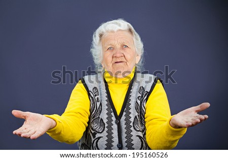 Closeup portrait, clueless senior, mature, elderly woman, arms out asking why whats problem who cares so what I don\'t know, isolated black background. Negative human emotion, facial expression feeling