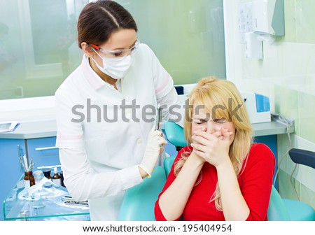 Closeup portrait young terrified girl woman scared at dentist visit, siting in chair, covering her mouth, doesn\'t want dental procedure, drilling, tooth extraction, isolated clinic office background