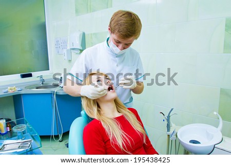 Closeup portrait young female, woman, patient sitting in dentist chair, office with wide open mouth getting oral thorough examination done by doctor in mask isolated background clinic office equipment