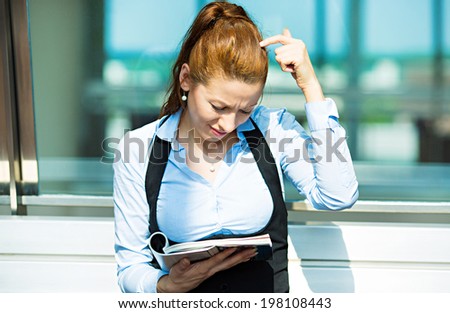 Closeup portrait confused, puzzled, surprised business woman reading latest news in magazine, unexpected stock market news isolated background corporate office windows. Human facial expression emotion
