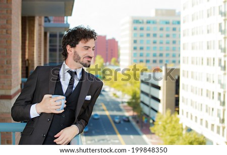 Closeup portrait happy handsome young man with cup of coffee, enjoying life on outside balcony background trees, city buildings. Urban life style. Male model, corporate life success. Positive emotions