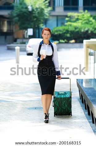 Business woman going on trip. Portrait businesswoman, company employee, attractive corporate executive, young model crossing street, traveling with luggage, handbags in the city, holding cup of coffee