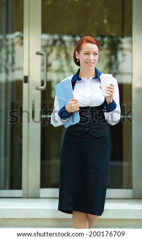 Portrait attractive young business woman leaving her corporate office, walking outdoors on summer day, holding cup of coffee, documents. Positive face expressions, emotions, life perception, lifestyle