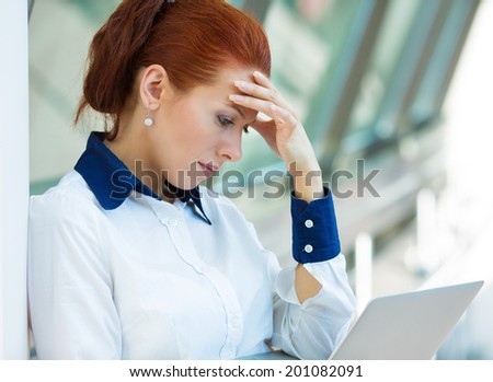 Closeup portrait unhappy business woman, hand on head standing, bothered by mistake, reading email, bad news on computer having headache isolated background corporate office. Negative face expression