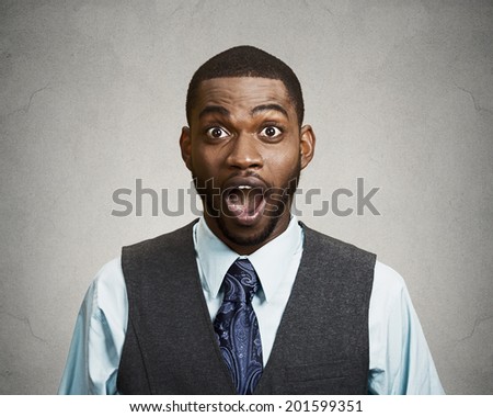 Closeup portrait happy young man, wide open mouth looking shocked, surprised in full disbelief isolated black grey background. Positive human emotions, facial expressions, feeling, attitude, reaction