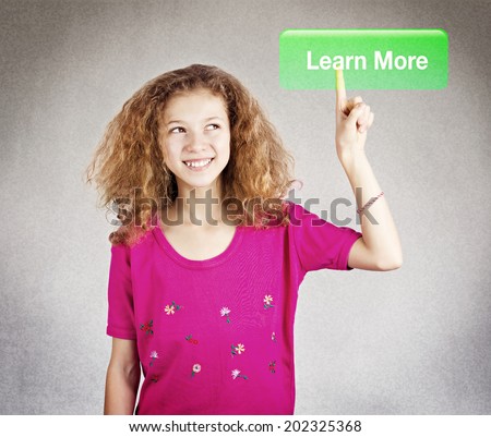 Closeup portrait young happy, smiling girl pressing digital learn more button on interface in front of her, isolated grey black background. Education, school, college concept. Positive face expression