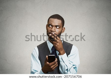 Closeup portrait puzzled confused business man looking up thinking what to reply to received text message on cell phone, texting isolated black background. Human face expression reaction body language
