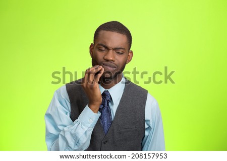 Closeup portrait handsome sad young executive man, student, worker touching face having bad pain, tooth ache, isolated green background. Negative human emotions, facial expressions, feeling reaction