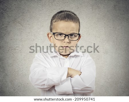 Closeup portrait Angry, displeased child Boy looking at you camera, arms folded, insists on his position isolated grey wall background. Negative human emotions, feelings, facial expression, perception