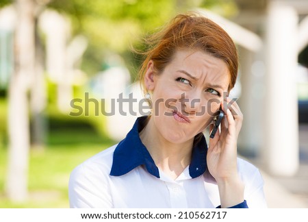 Closeup portrait upset sad, skeptical, unhappy, serious woman talking on phone, displeased with conversation isolated outdoor background. Negative human emotion facial expression feeling. Bad news