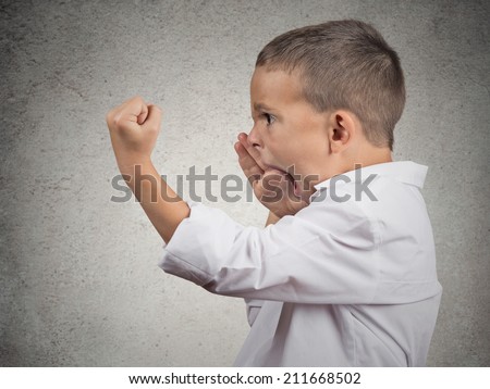 Closeup Headshot side view Portrait Angry Child Screaming, fists up in air isolated grey wall background. Negative Human face Expressions, Emotion, Reaction, Perception. Conflict confrontation concept
