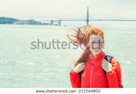 San Francisco female on boat with Golden Gate Bridge in background with sun light glare. Young attractive, girl happy joyful. California tourism concept with cheerful tourist. Positive face expression