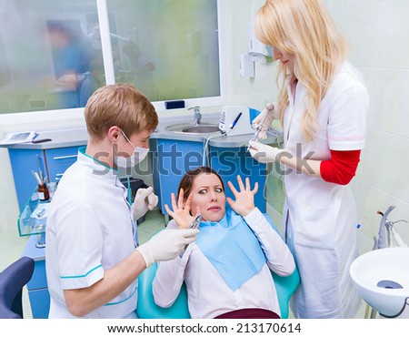 Closeup portrait young terrified girl woman scared at dentist visit, siting in chair, screaming, opened mouth, doesn\'t want dental procedure drilling tooth extraction isolated clinic office background