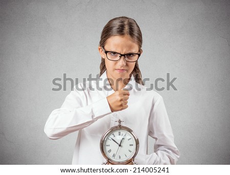 Portrait angry, mad, pissed off teenager girl pretending to be boss manager about to smash alarm clock with fist isolated grey wall background. Negative human emotion facial expression strict attitude