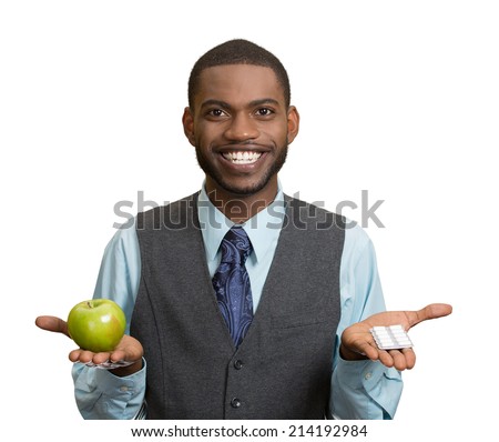 Portrait young, fit, happy handsome man holding green fresh apple in one hand, pills, vitamins in another. Sugar free chewing gum, dentist recommended. Face expressions, emotion, health care. Dieting