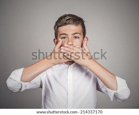 Portrait young man, student, boy, covering his mouth with hands. Speak no evil concept, isolated grey wall background. Human emotions, face expressions, feelings, signs, surrounding perception