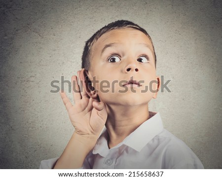 Curious man, boy, listens. Closeup portrait child hearing something, parents talk, hand to ear gesture isolated grey wall background. Human face expression, emotion, body language, life perception