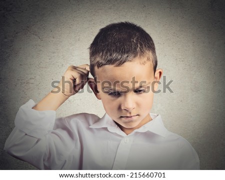 Thinking child, scratching back of his head isolated grey wall background. Human face expressions, emotions, body language