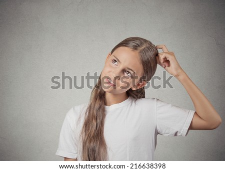 Confused, remembering. Portrait teenager girl scratching head, thinking daydreaming about something, looking up isolated grey wall background. Human facial expression, emotion, feeling body language