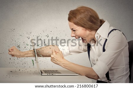 Angry furious businesswoman throws a punch into computer, screaming. Negative human emotions, facial expressions, feelings, aggression, anger management issues concept