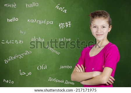 Learning foreign languages. Portrait confident teenager girl student standing by chalkboard with word hello written in different foreign languages. Education concept, international communication