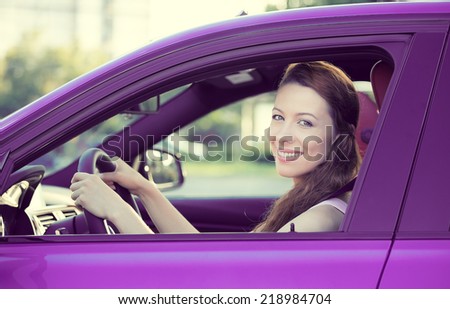 Portrait smiling, attractive happy woman, buckled up, driving, testing her new violet car, automobile, purchased at dealership, isolated street, city traffic background. Safe driving habits concept