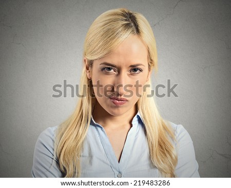 Closeup portrait displeased, pissed off, angry, grumpy, young woman with bad attitude, looking at you, isolated grey wall background. Negative human emotions, facial expressions, feeling body language