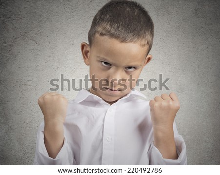 Closeup portrait angry child boy with fist up in air, pissed off looking grumpy isolated grey wall background. Negative human Emotions Facial Expression body language attitude perception confrontation