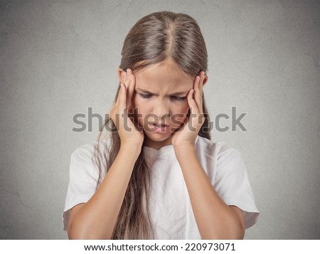 Closeup portrait stressed child, teenager girl hands on temples overwhelmed at school in life, isolated grey wall background. Human facial expressions, emotions, feeling, perception