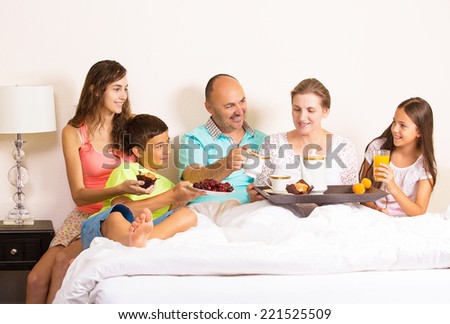 Group portrait happy smiling joyful family, mother, father, daughters, son having breakfast  together in bed, surprise on mom day. Positive human emotions, face expressions, feelings, life perception