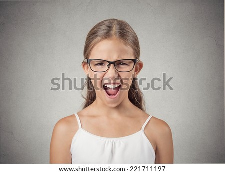 portrait headshot angry child teenager girl screaming wide open mouth isolated grey background. Negative human face expression emotion reaction perception body language. Conflict confrontation concept