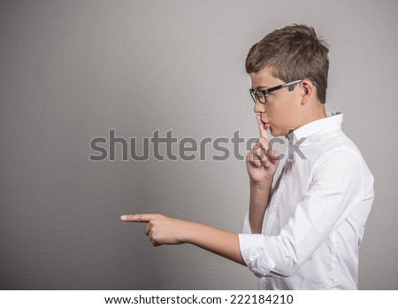 Closeup side view profile portrait young man placing finger on lips and pointing to say, shhh be quiet, isolated on white background. Negative facial expression emotion signs symbols, body language