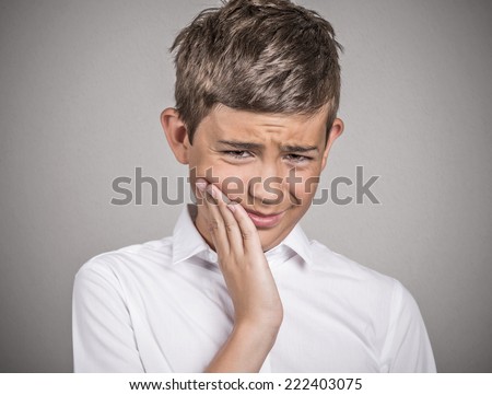 Closeup portrait young sad man with sensitive tooth ache, crown problem, touching outside mouth with hand, isolated grey background. Negative human emotion, facial expression, feelings, reaction