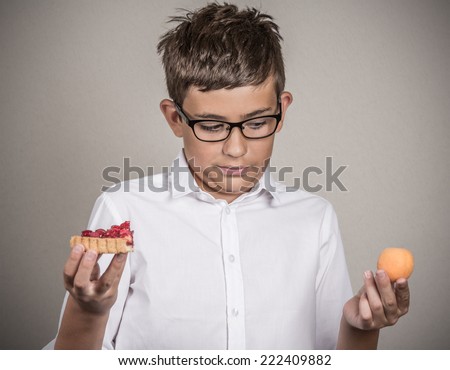 Closeup portrait young man with glasses deciding on diet, making choice sweet cookie tart fresh fruit apricot isolated grey background. Weight control eating habits. Confused face expression, emotion